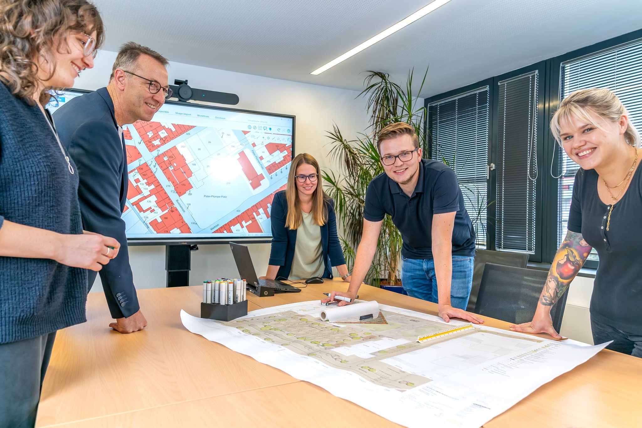 The picture shows a group of people bending over a map lying on a table.