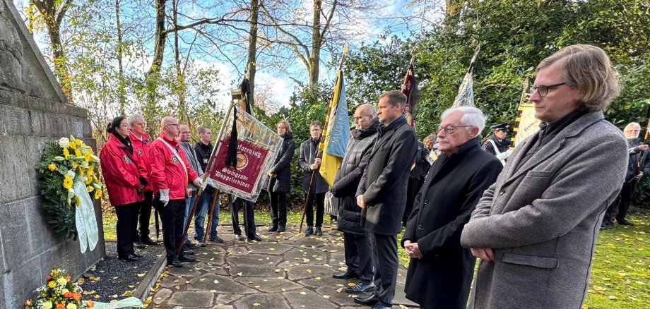 Members of the social clubs, the head of the village and the mayor stand in front of the memorial in Marienpark