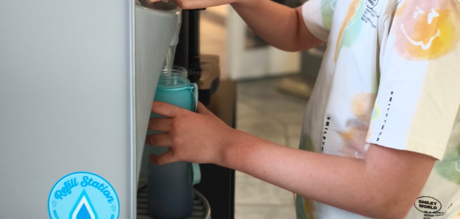 A child fills up his drinking bottle at a water dispenser.
