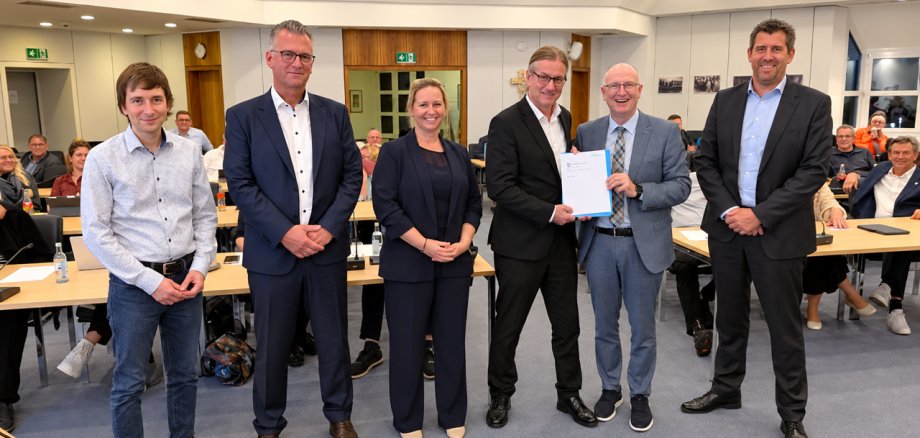 De voorzitter van de GPA overhandigt de burgemeester een verslag. Naast hem staan drie mannen en een vrouw