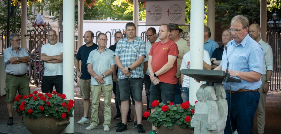 Fundusz "Energia dla Kevelaer Wolfgang Toonen stoi przy mównicy w Forum Pax Christi. Za nim zgromadzili się przedstawiciele klubów strzeleckich.