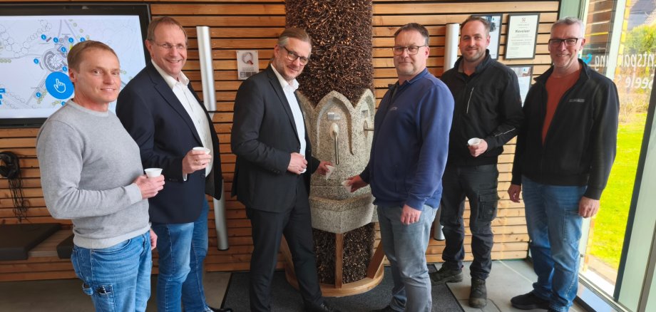 Кілька представників Stadtwerke Kevelaer та паломницького містечка Кевелаер стоять біля нового питного фонтану в соляному саду Святого Якоба.