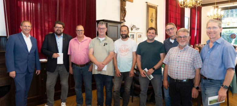 Фонд "Енергія для Кевелера Кілька чоловіків і жінок стоять поруч і тримають у руках конверт.