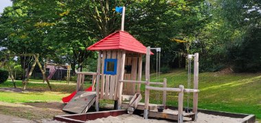 Дитячий майданчик Heinestraße у Кевелаері Великий дерев'яний скеледром з пісочницею на дитячому майданчику.