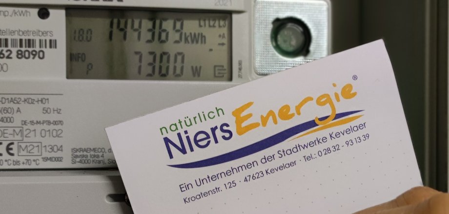 Рука записує показання лічильника на блокноті - на задньому плані видно лічильник електроенергії.